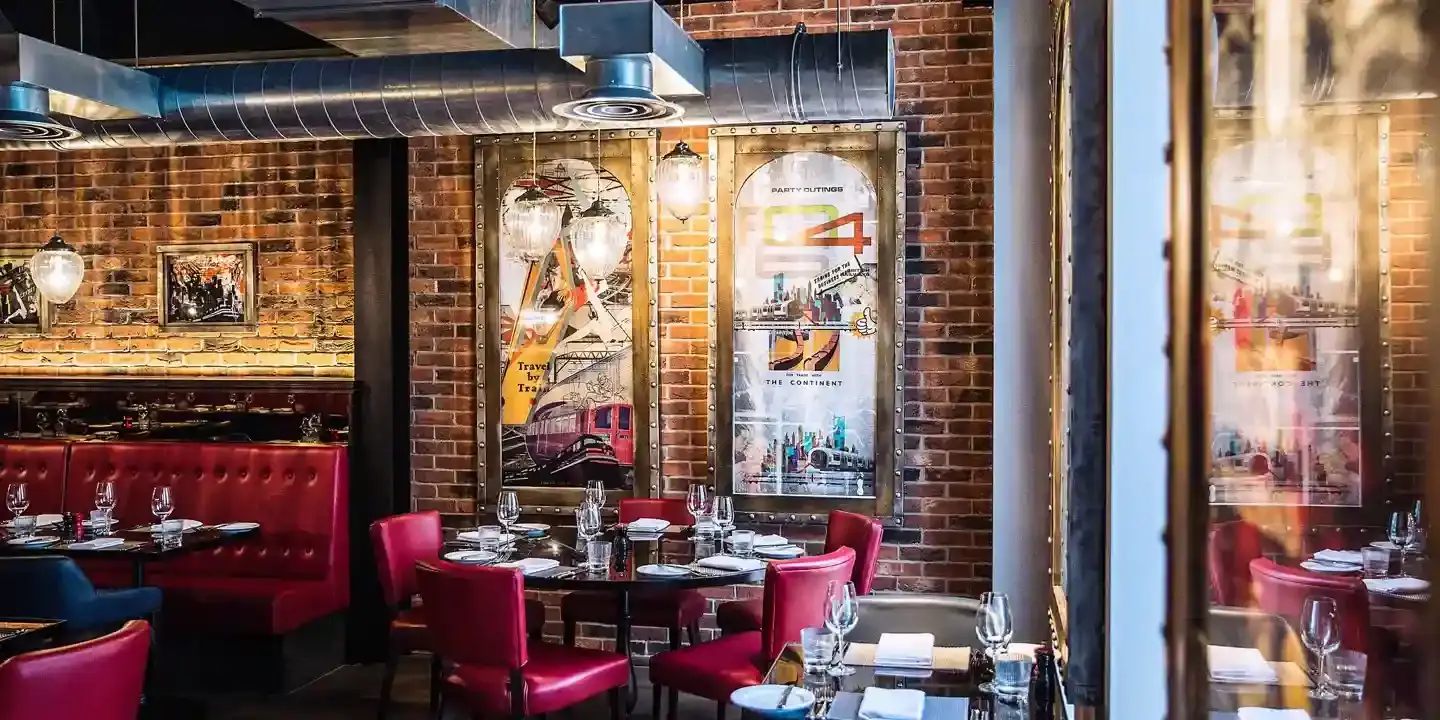 A restaurant featuring a brick wall backdrop and red booths.