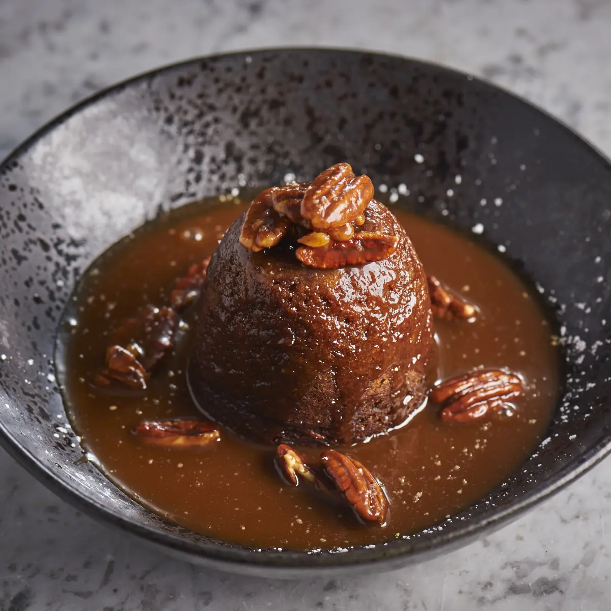 A person pouring gravy onto a plate of food