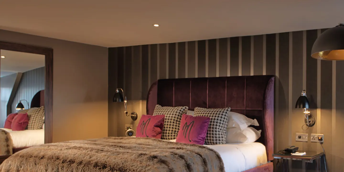 Bedroom featuring a comfortable bed with pink velvet headboard and a mirror.