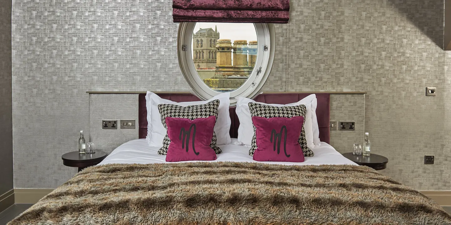 Spacious bedroom featuring a king-sized bed and a circular window.