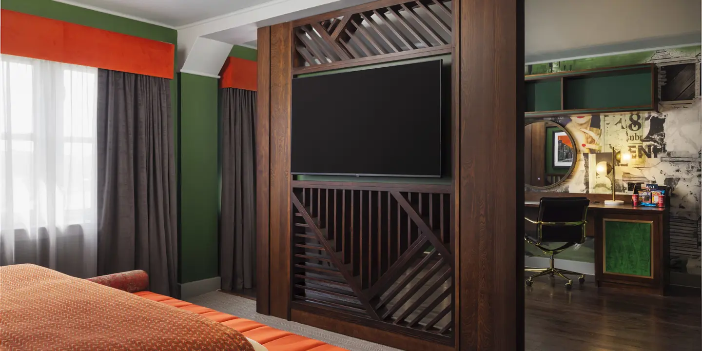 Spacious room with comfy bed, ottoman, wall-mounted TV, desk and chair