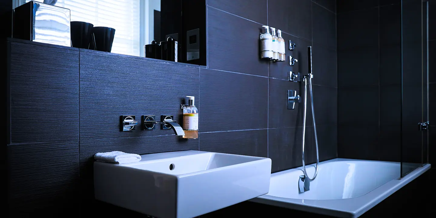 A black bathroom featuring a white sink and bathtub.