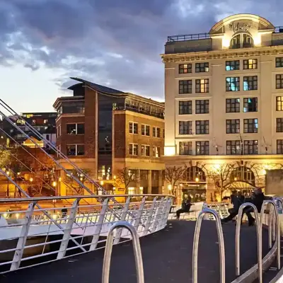 A bridge spanning a river with a well lit building in the background.