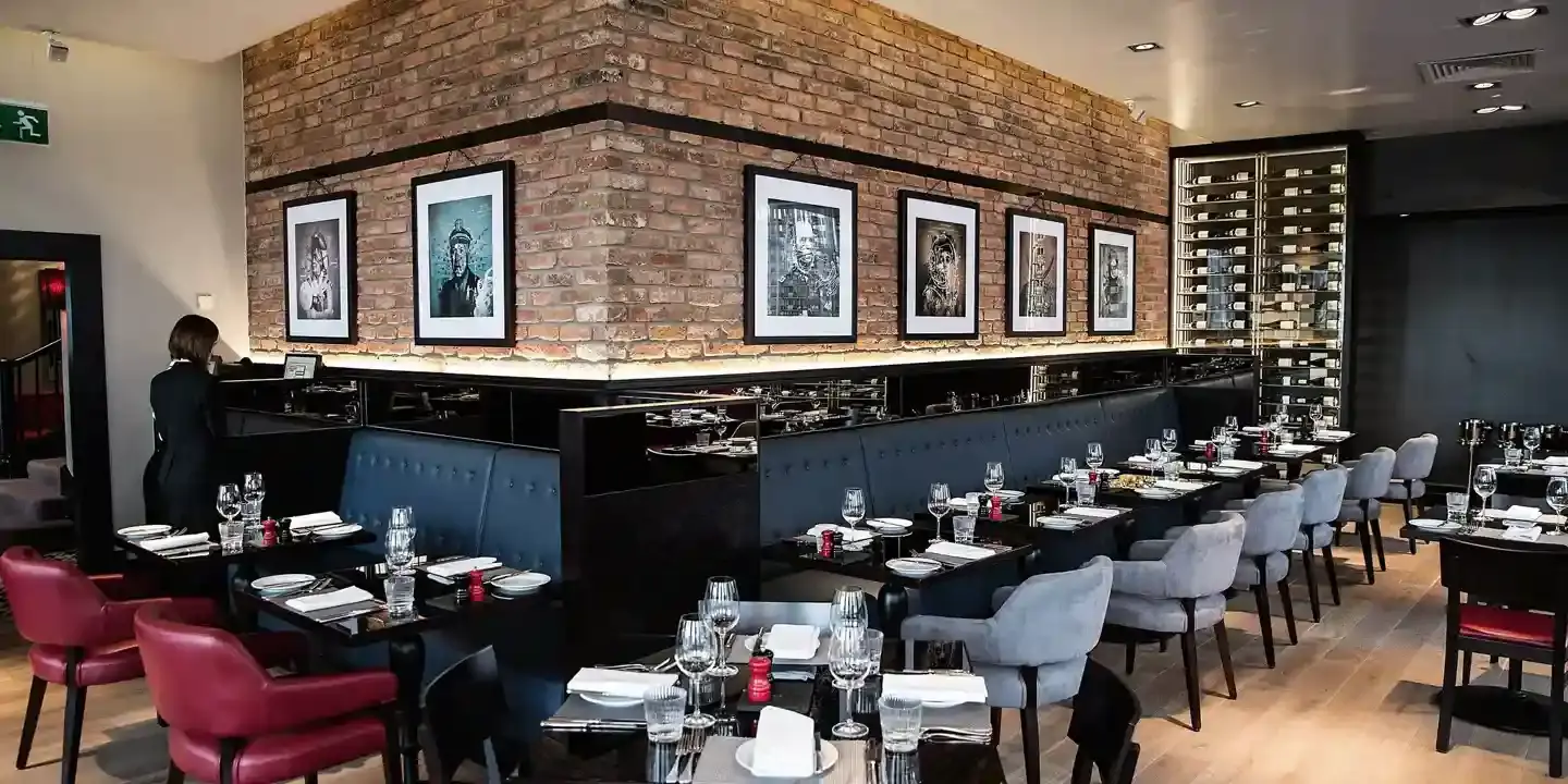 A restaurant featuring a brick wall, accompanied by tables and chairs.