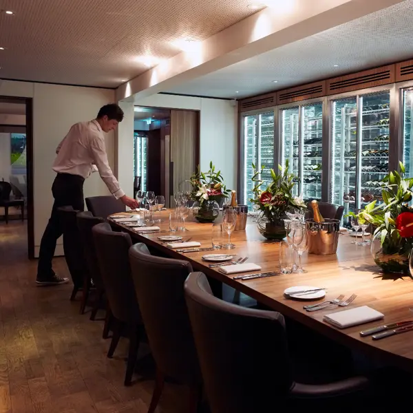 A man is arranging a long table in a restaurant.