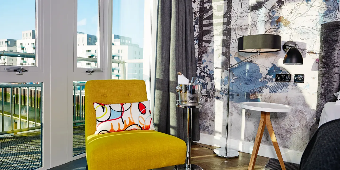 A yellow chair positioned in front of a window.