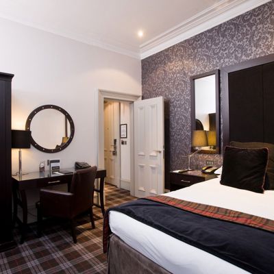 A bedroom featuring a sleek black headboard with tartan print and a desk.