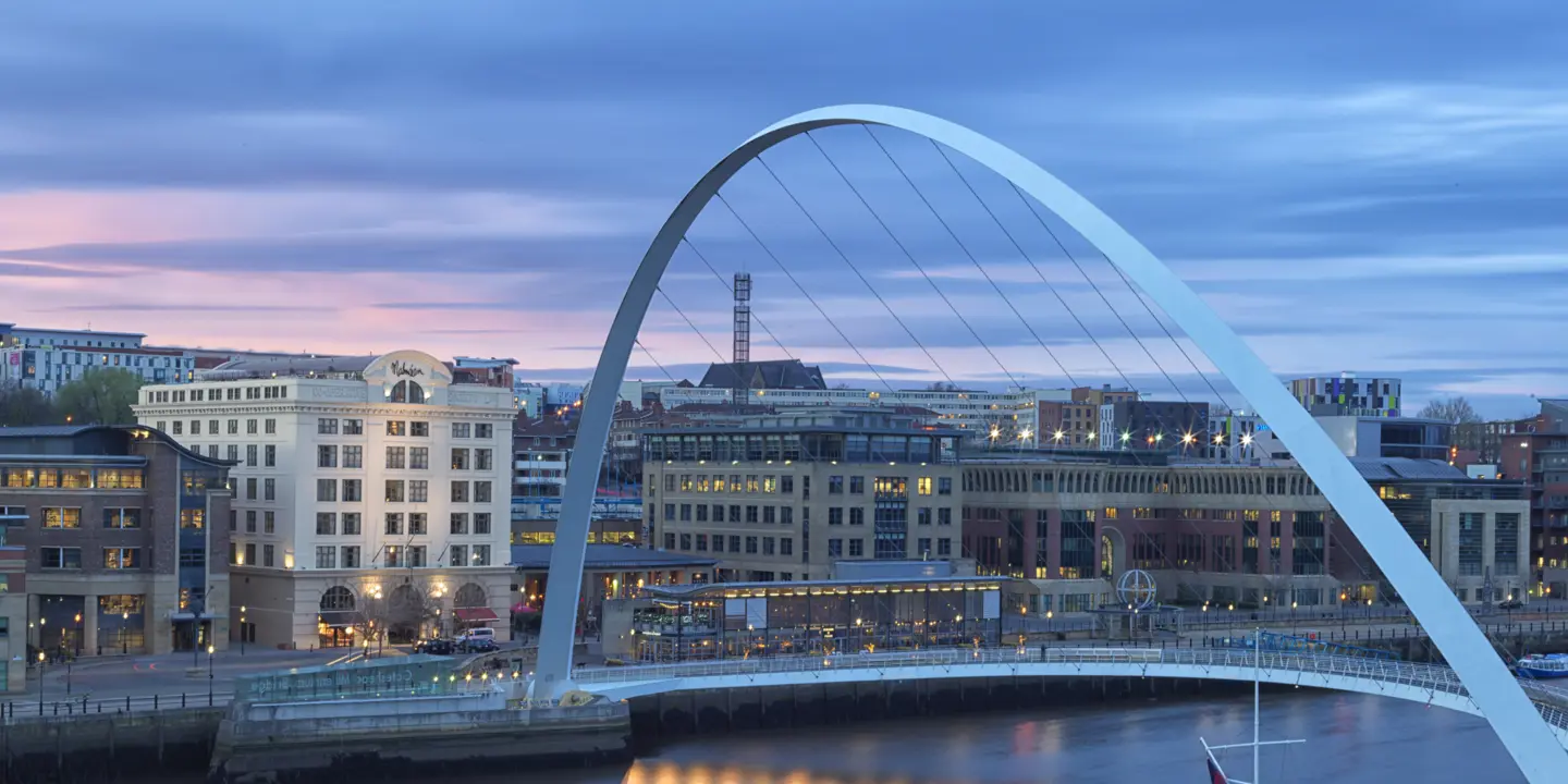 A bridge spanning a body of water with buildings in the background.