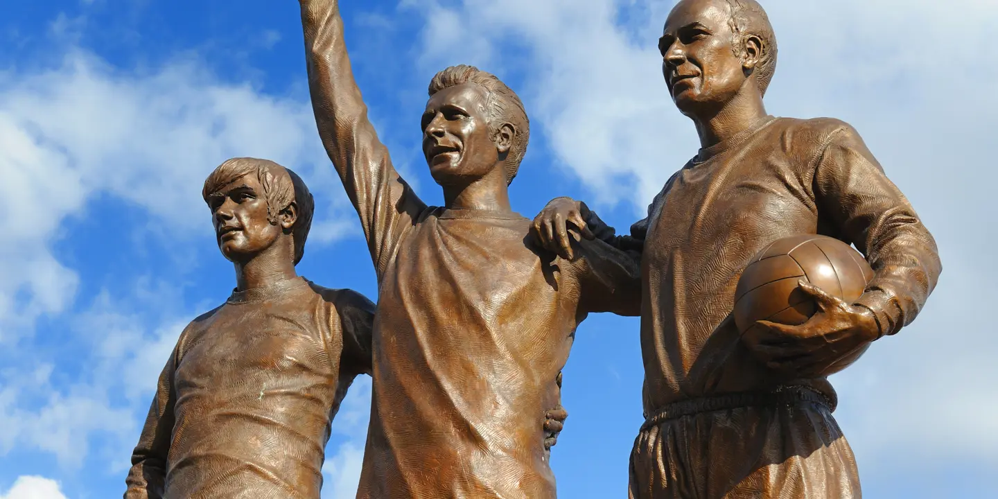 Statue of three men holding a ball.