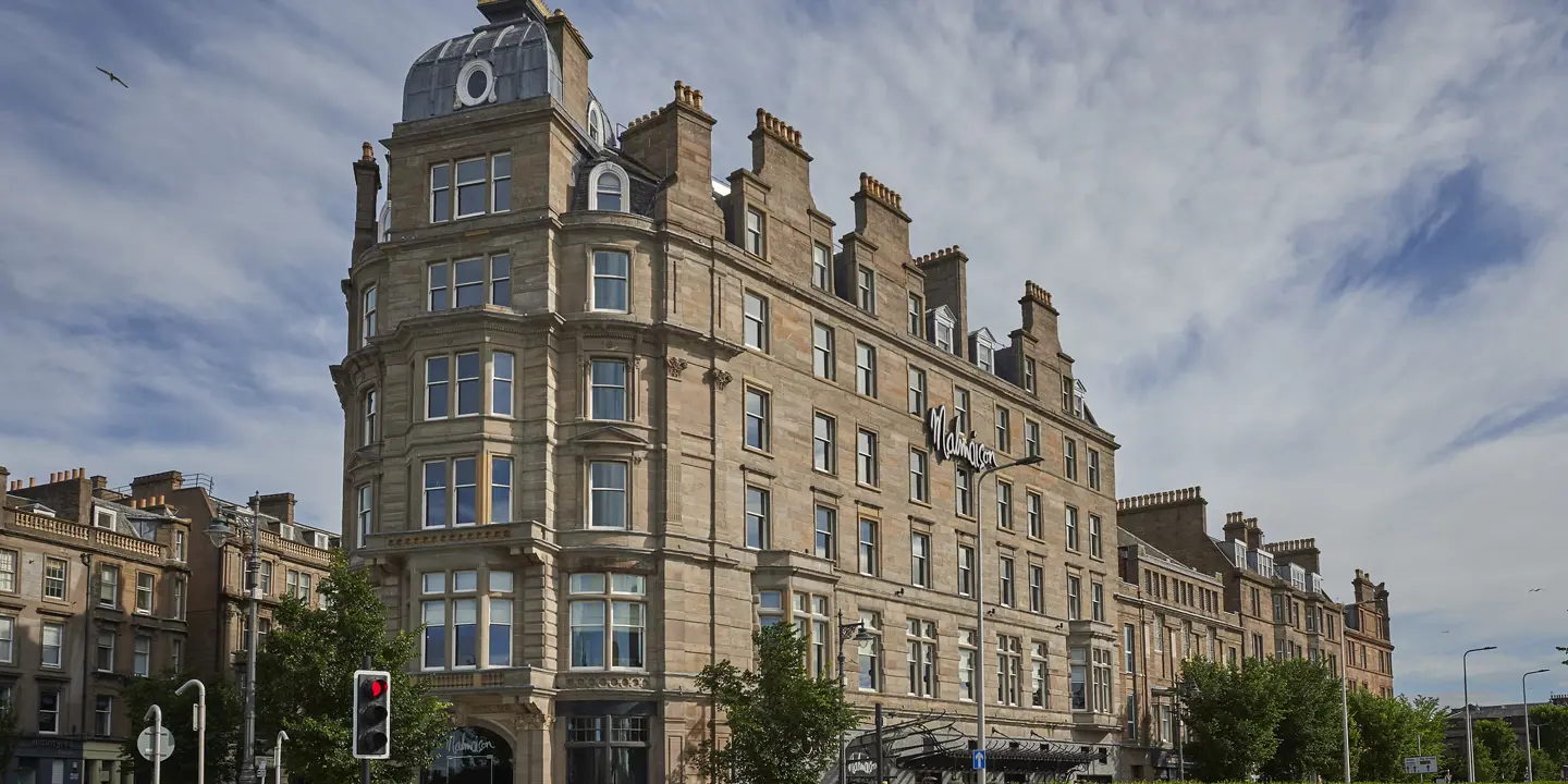 A tall building with numerous windows on a bustling city street.