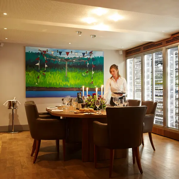 A lady arranging a long table with glasses.