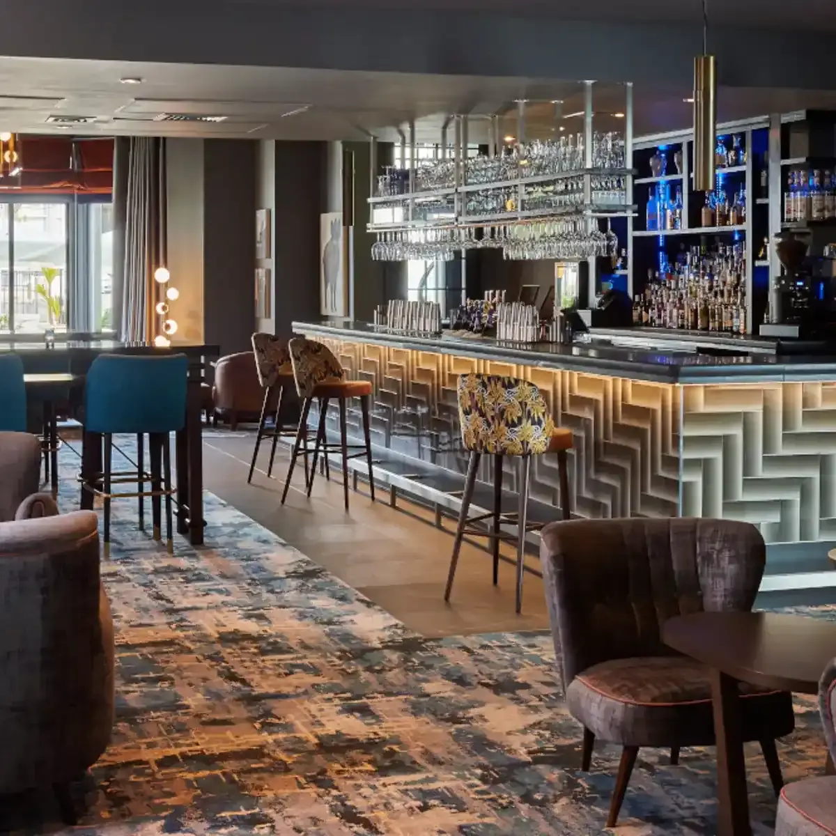 The bar adorned with numerous chairs and tables, and multiple glasses hanging from a ceiling rack