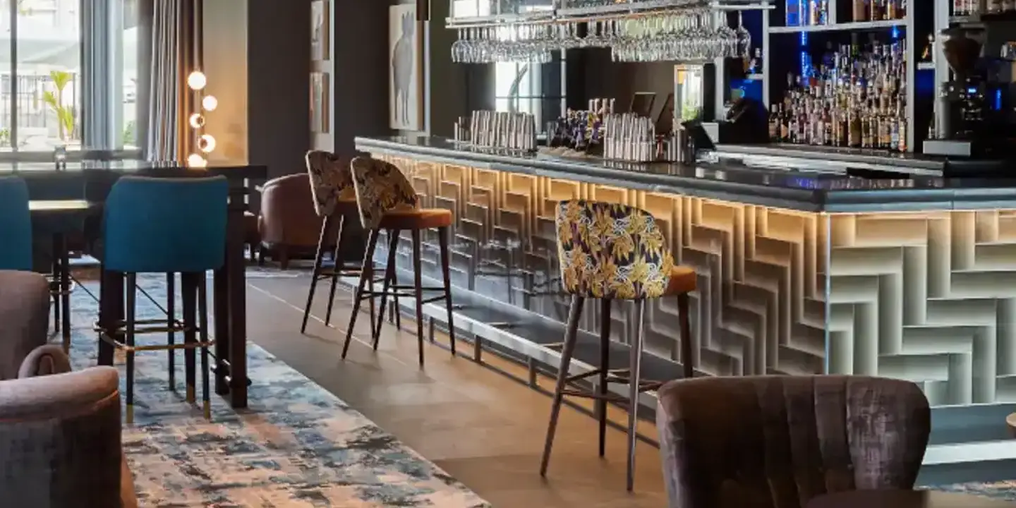 The bar adorned with numerous chairs and tables, and multiple glasses hanging from a ceiling rack