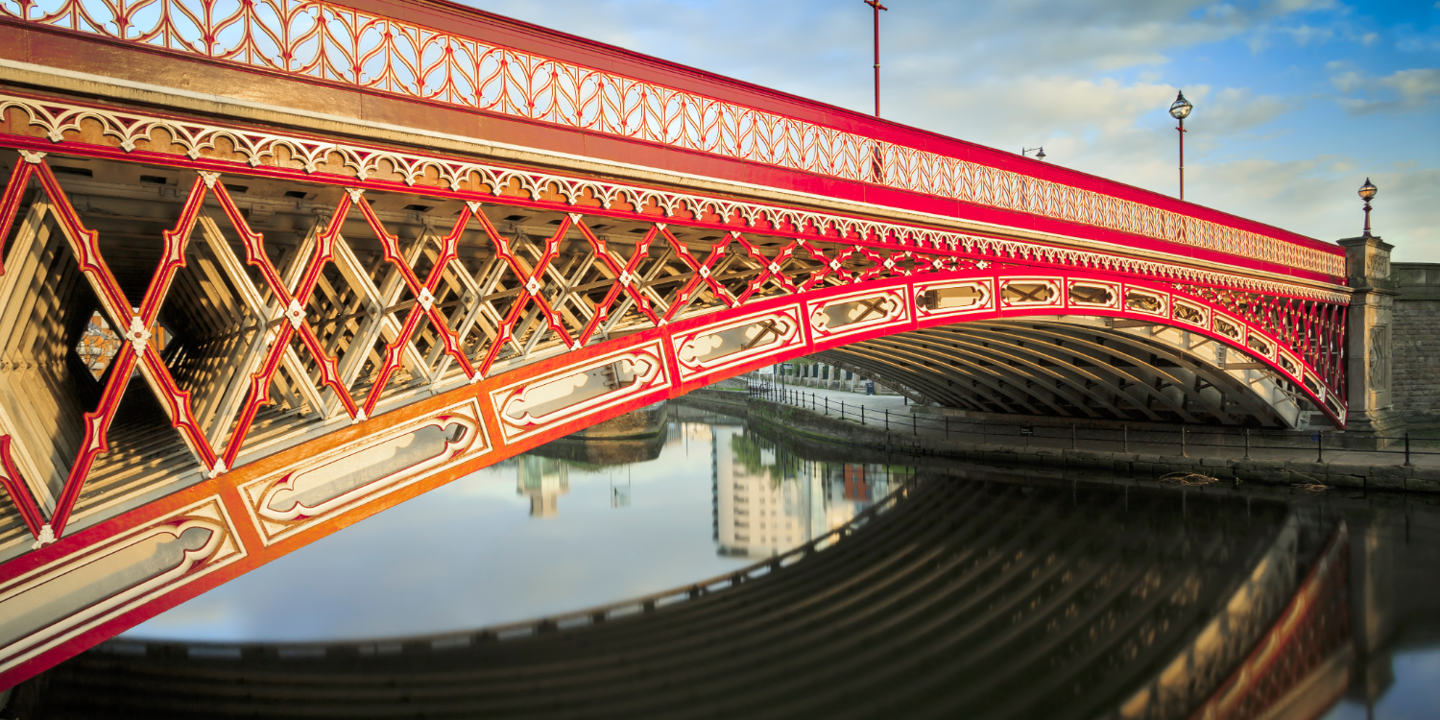 Red bridge spanning across a serene body of water.