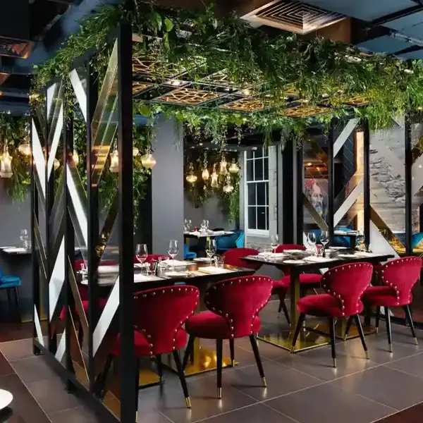 An image of a restaurant featuring a lengthy table adorned with red chairs.