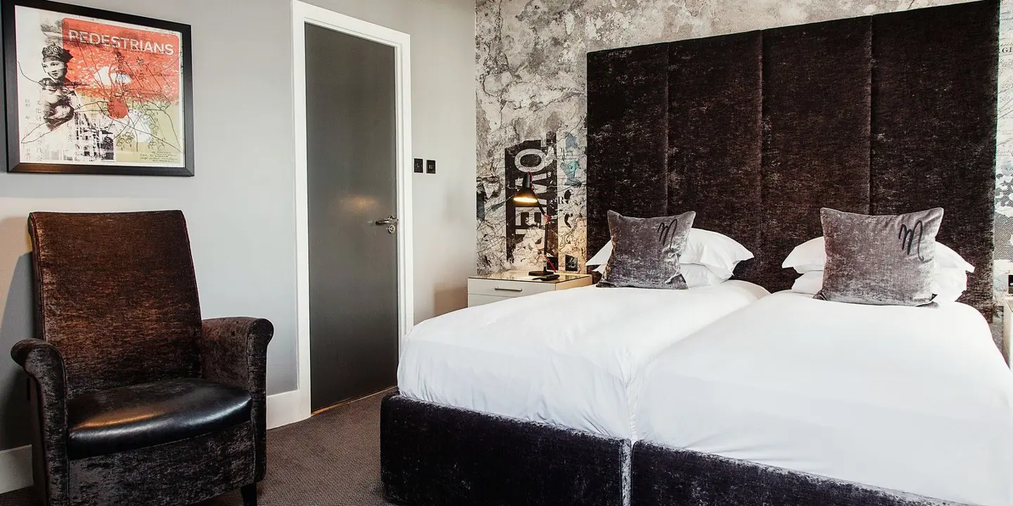 Bedroom featuring a grey velvet bed with a grey arm chair.