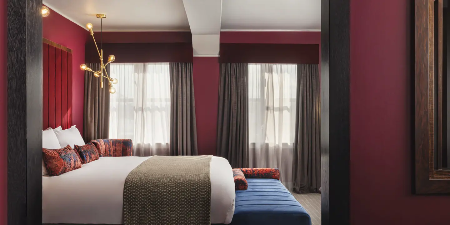 Spacious room with large luxurious bed, armchair and ottoman 
