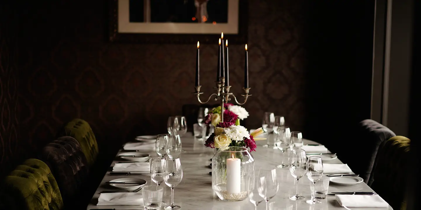 A table arranged for a formal dinner in a dimly lit room.