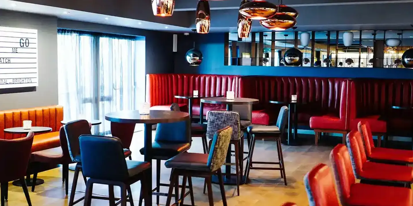 A bar featuring numerous tables and chairs, booth seating areas, and feature copper light fittings.