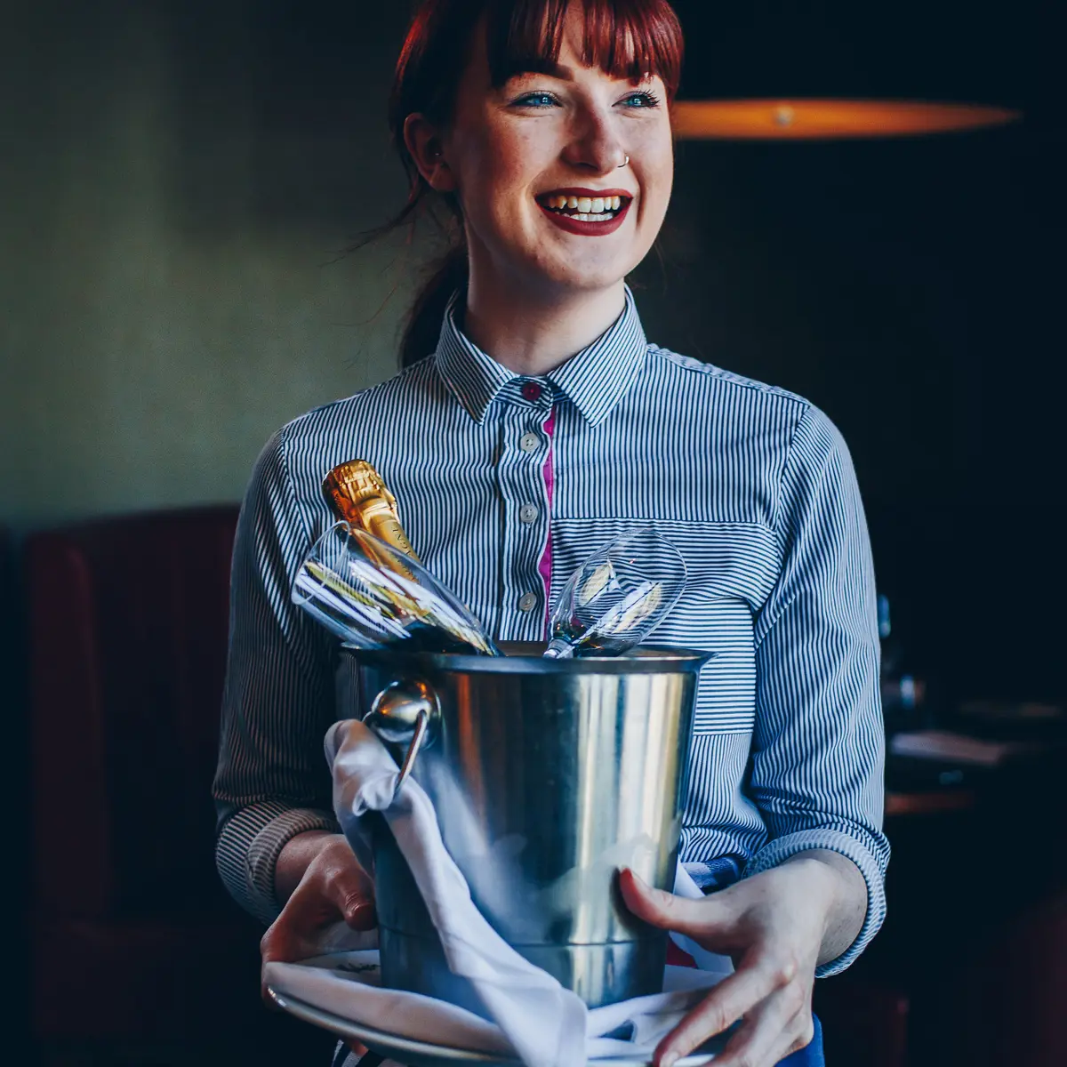 Housekeeper holding tray with champagne and wine glasses