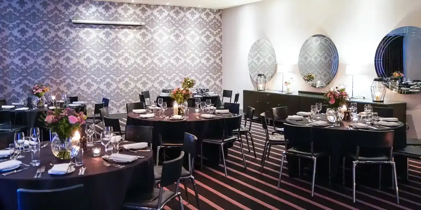 A dining room set with tables and chairs arranged for a dinner gathering.