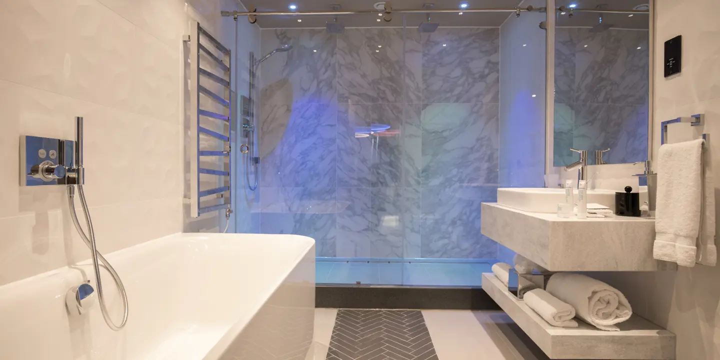 Spacious bathroom featuring a large walk in shower, bath and marble sink.