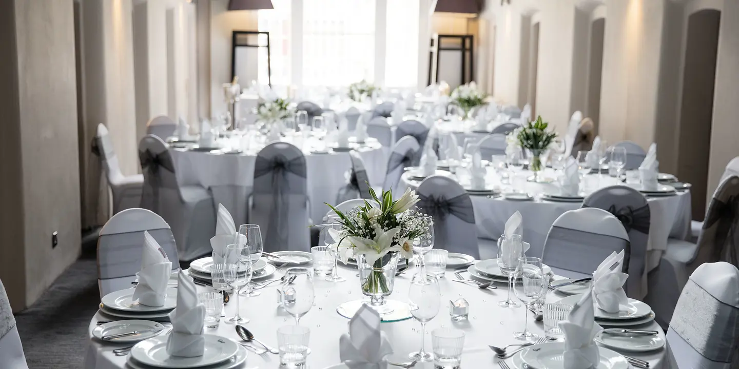 A room adorned with white tablecloths draped over tables.