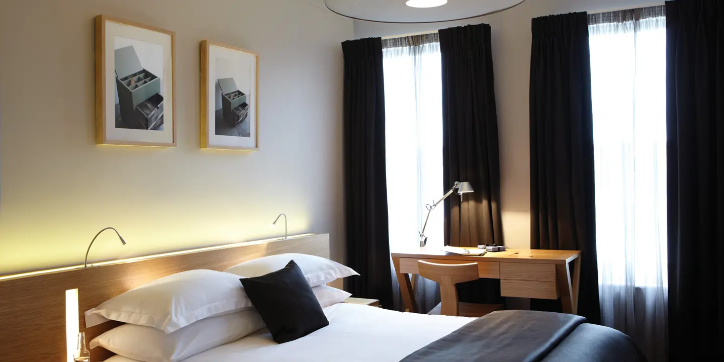 Bedroom featuring a fresh white bed, desk and black accessories. 