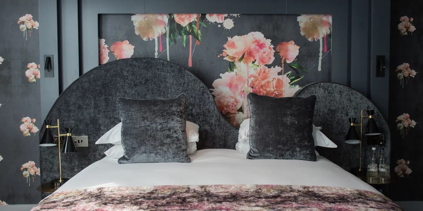 An elegantly made bed adorned with two plump pillows and a tasteful wall painting.