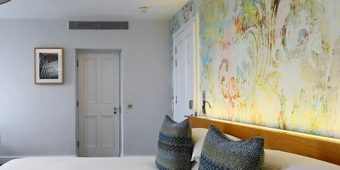 Bedroom featuring a comfortable bed and vibrant patterned wallpaper.