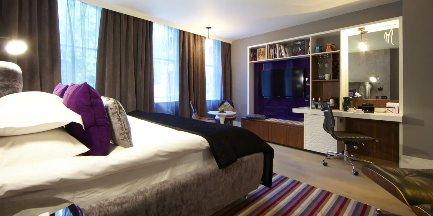 A well-arranged bedroom featuring a neatly made bed and a television.