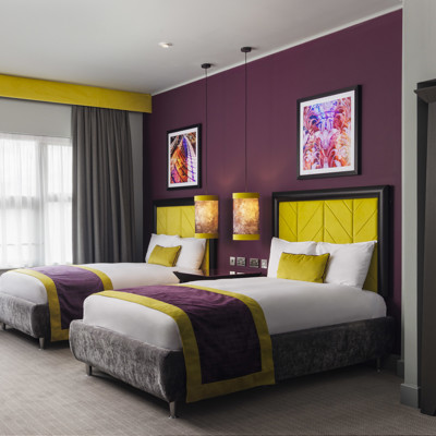 A spacious room with two double beds and a stylish chair.