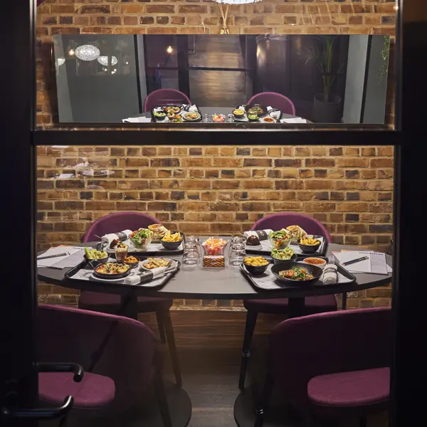 Plates of food arranged on a table in front of a brick wall.