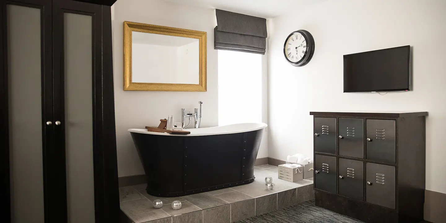 Black bathtub and mirror in a bathroom.